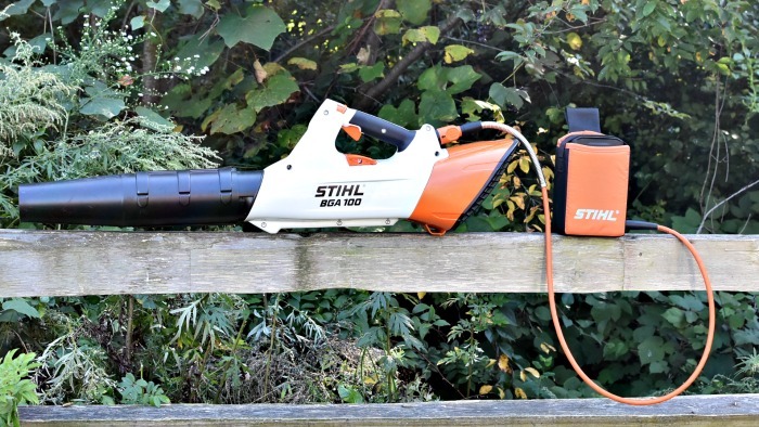 Stihl BGA 100 Battery Blower sitting on fence rail with woods in the background. 