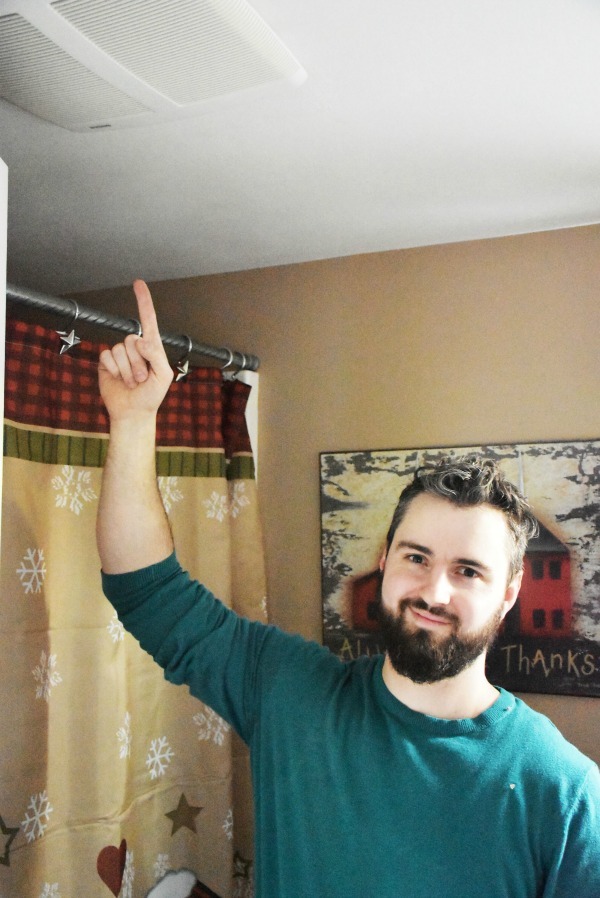 man pointing at new bathroom exhaust fan in ceiling