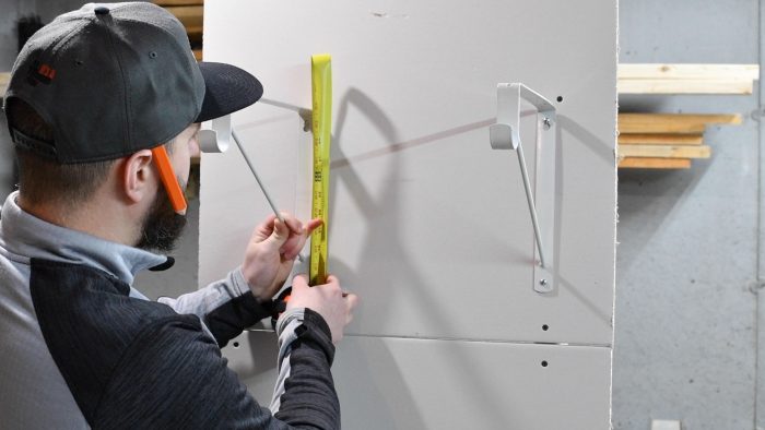 measuring the height of a shelf bracket with a tape measure