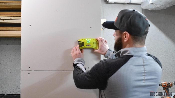 man using a stud finder on wall