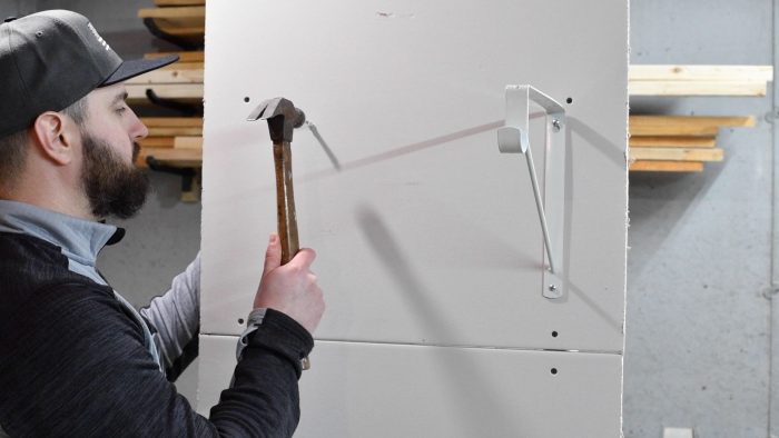 man hammering a wall anchor into a wall