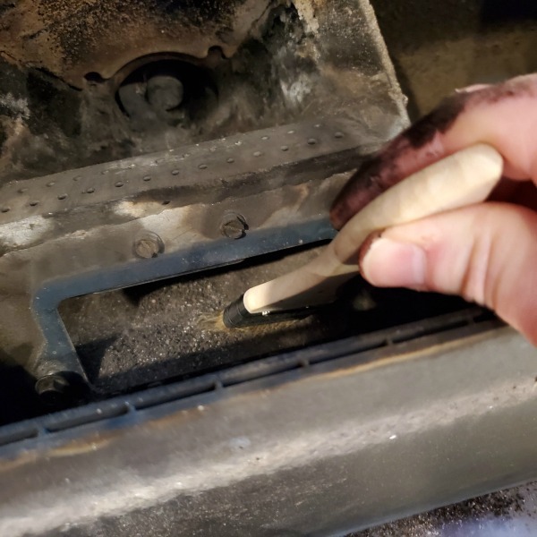 using a chip brush to sweep ash out of the igniter cavity.