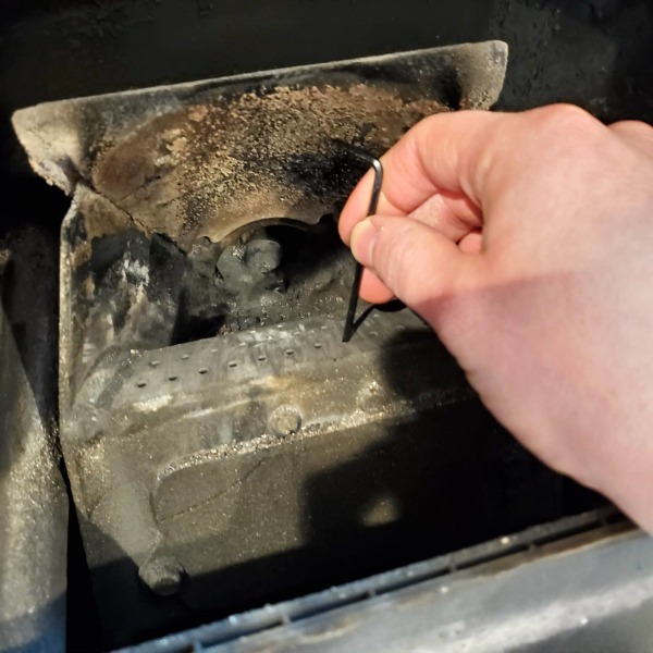 sticking a small allen wrench into one of the holes in a pellet stove burn pot grate