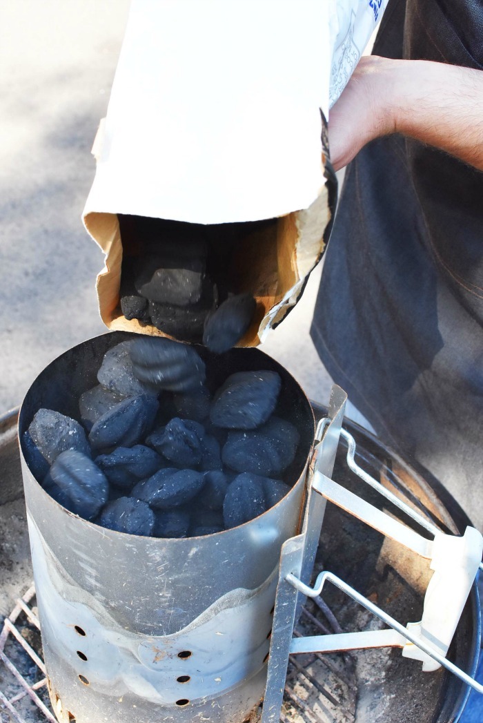 pouring charcoal into chimney from bag. chimney is full.